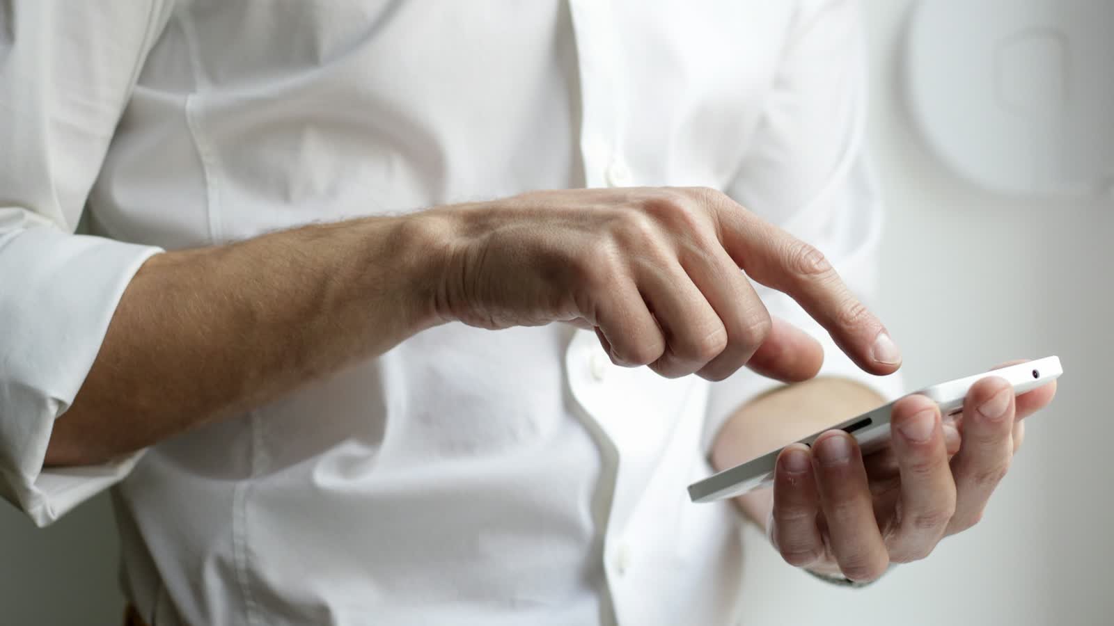 A person holding a smartphone in both hands while using an app