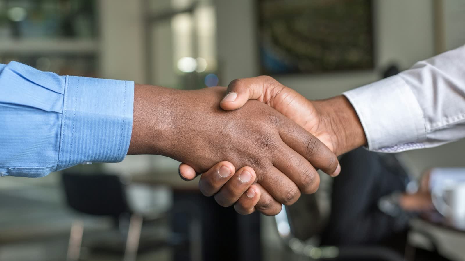 Two people shaking hands across a table in an office