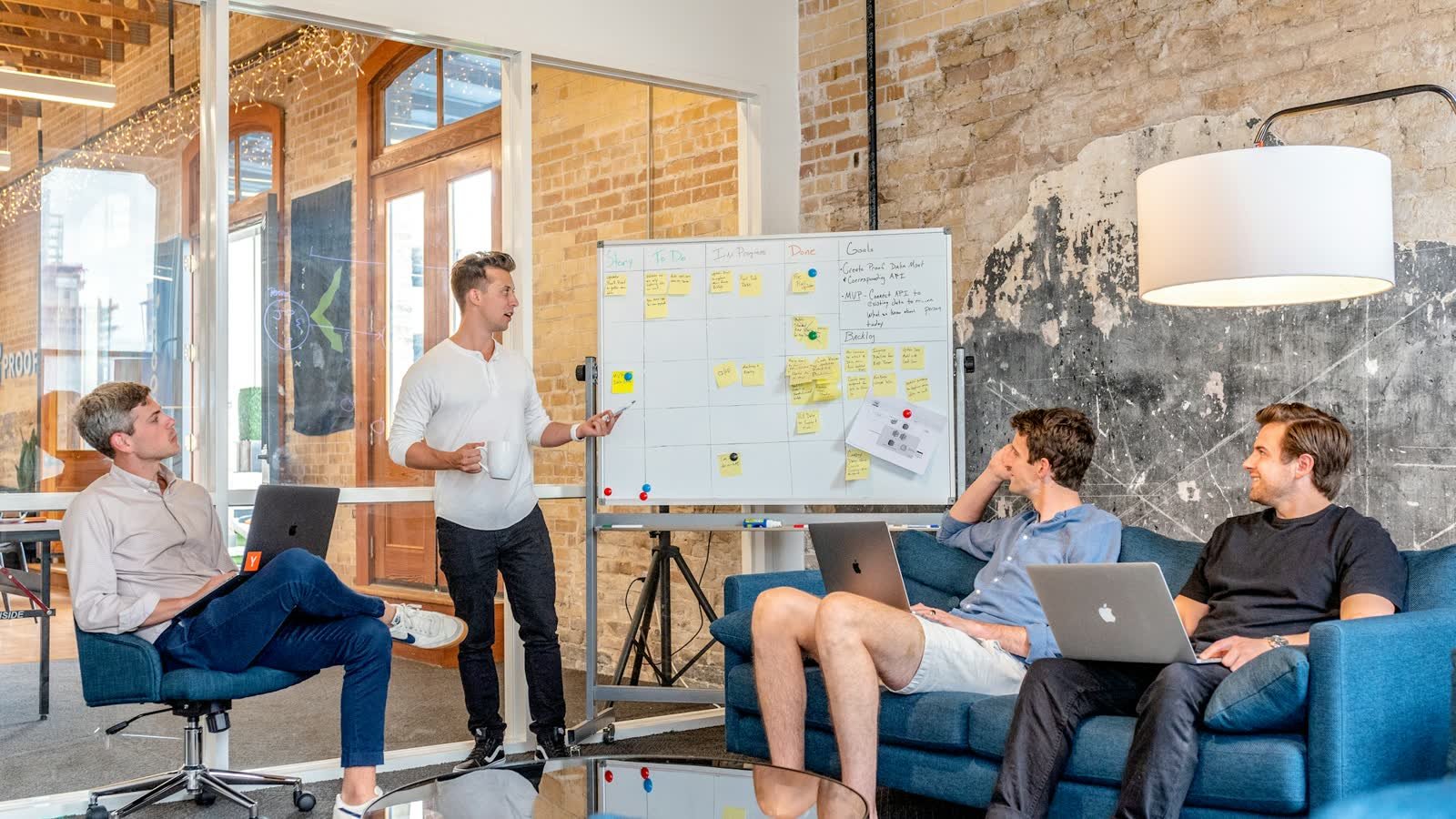 A project team reviewing a whiteboard planning board covered in sticky notes during a meeting