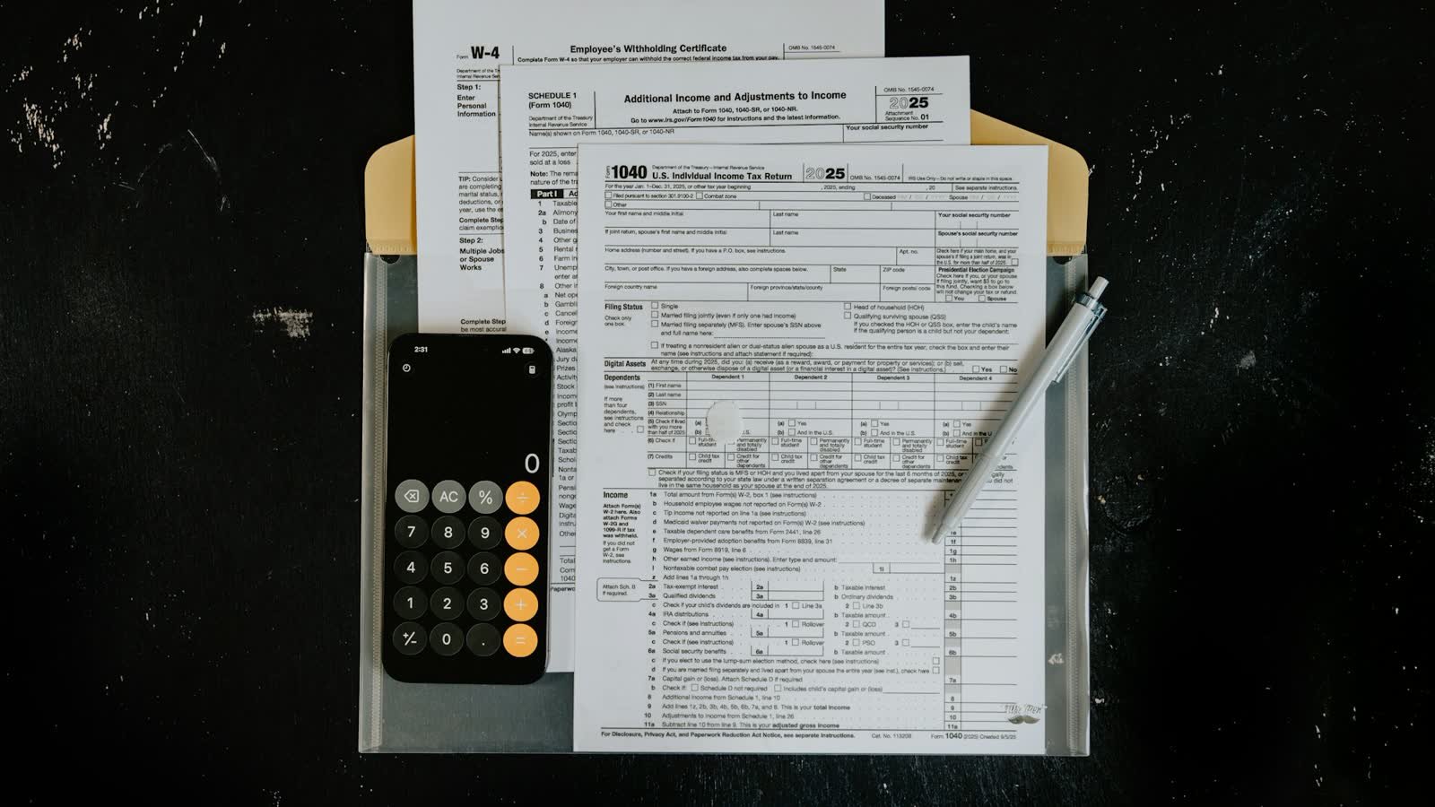 Tax forms on a clipboard beside a calculator and pen on a dark desk