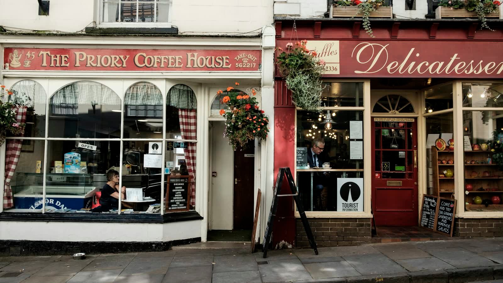 A row of small shopfronts on a street, a coffee house beside a delicatessen